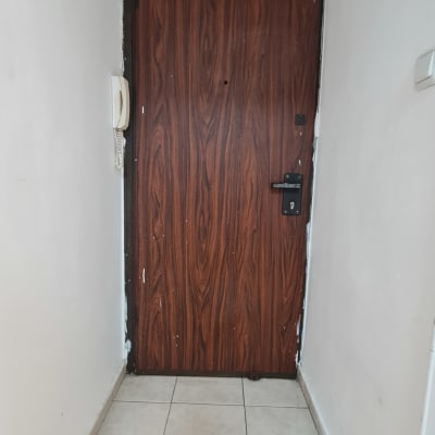 דלת עץ חומה עם ידית שחורה וקיר לבן