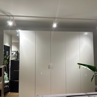 ארון לבן עם תאורה עליונה וצמח ירוק בצד