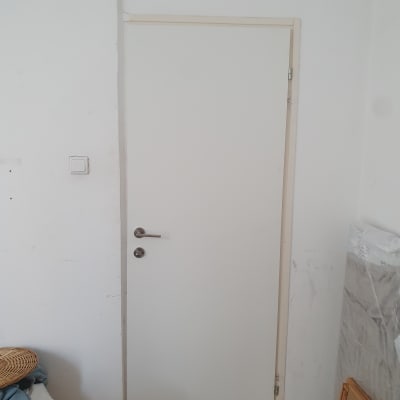 דלת לבנה עם ידית מתכת על קיר לבן