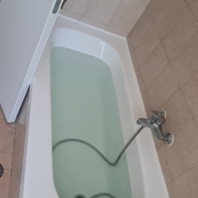 אמבטיה עם מים וברז מתכת על קיר אריחים