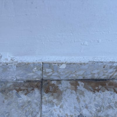 רצפה מלוכלכת עם כתמי לכלוך ליד קיר לבן