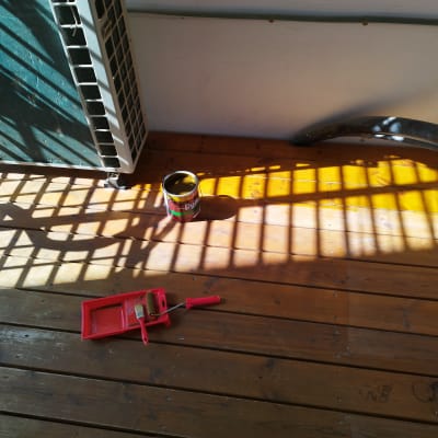 מברשת צבע ומגש על רצפת עץ עם פחית צבע