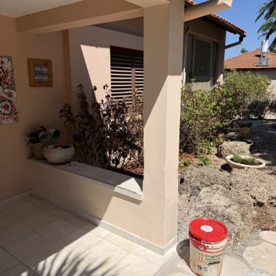 חצר וכניסה לבית פרטי לצד פח צבע במהלך שיפוץ קוסמטי