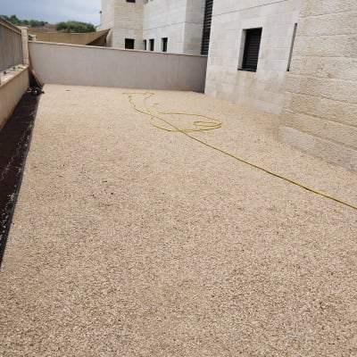 חצץ על הקרקע וצינור השקיה צהוב