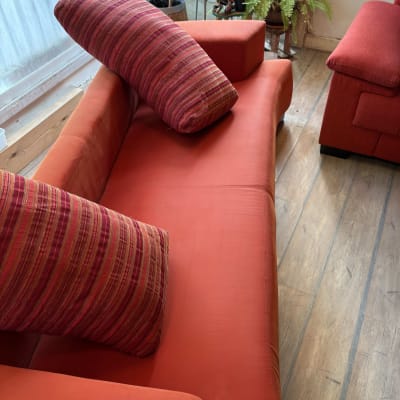 ספה אדומה עם כריות פסים על רצפת עץ