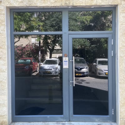 דלת כניסה עם אינטרקום ומכוניות חונות ברקע