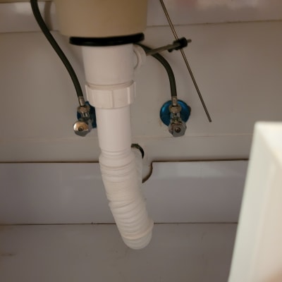 צינור פלסטיק לבן מתחת לכיור עם חיבורים