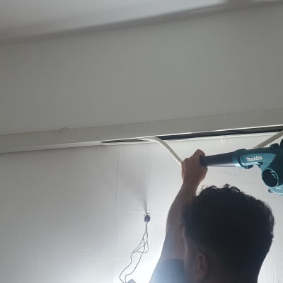 אדם משתמש במפוח ליד צינור מיזוג אוויר