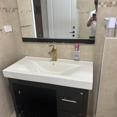 כיור אמבטיה עם ברז זהב ומראה, כלי עבודה על הרצפה