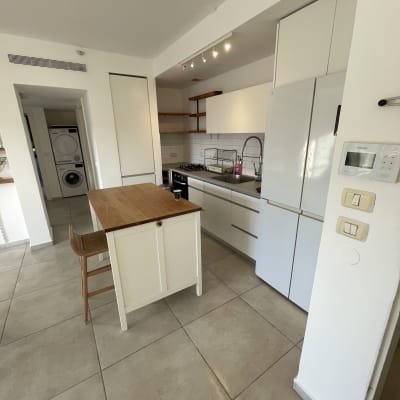 מטבח מודרני עם ארונות לבנים ותאורה עליונה