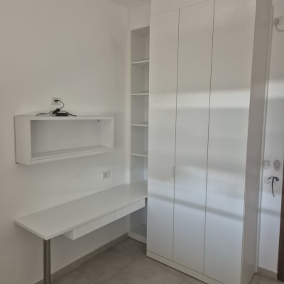 ארון לבן עם מדפים ושולחן עבודה צמוד לקיר