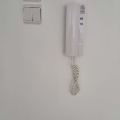 אינטרקום לבן עם שפופרת תלויה על הקיר