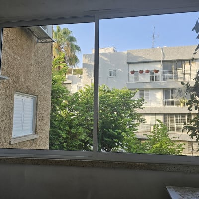 חלון אלומיניום עם נוף חיצוני של בניינים ועצים