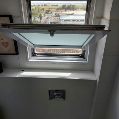 חלון אלומיניום פתוח עם מסגרת לבנה