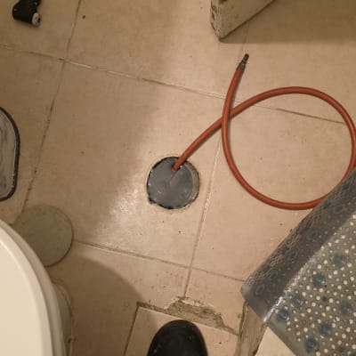 צינור כתום על רצפת חדר אמבטיה עם כלי עבודה