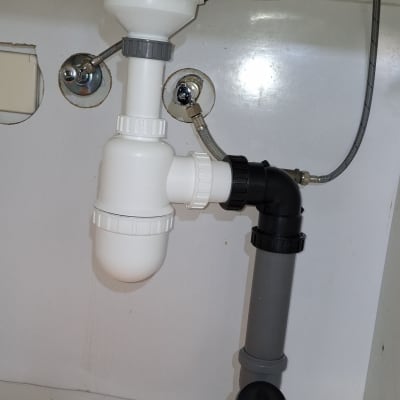 צנרת פלסטיק מתחת לכיור עם מגבת כתומה