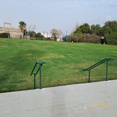 מעקה מתכת על מדרכה מול מדשאה ירוקה