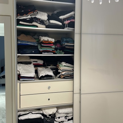 ארון בגדים פתוח עם מדפים ומגירות מלאים בבגדים מקופלים