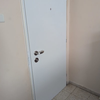 דלת לבנה עם ידית מתכת על קיר בהיר