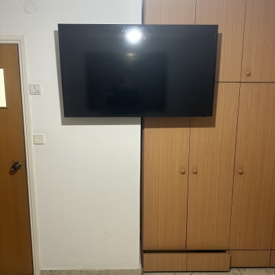 טלוויזיה מותקנת על קיר ליד ארון עץ