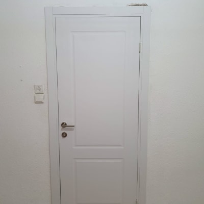 דלת לבנה עם ידית מתכת על קיר לבן