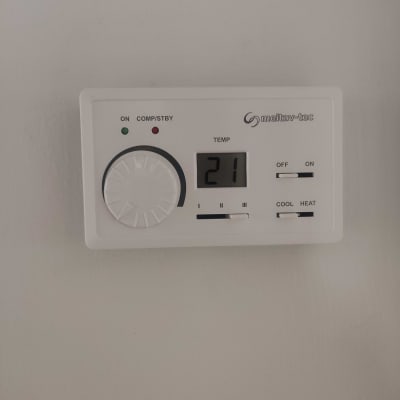 תרמוסטט מראה טמפרטורה 21 מעלות, כפתור וכפתורי הפעלה