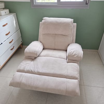 כורסה בחדר עם קיר ירוק ורהיטים לבנים