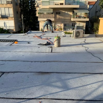 אדם עובד על איטום גג עם יריעות וחומרי איטום