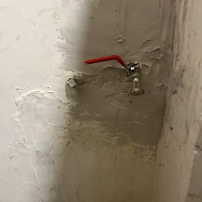 ברז עם ידית אדומה על קיר לבן