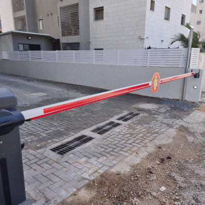 שער חשמלי עם מחסום אדום ולבן בכניסה לחניה
