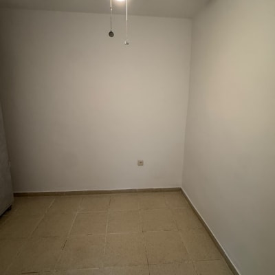 חדר ריק עם קירות לבנים, רצפת אריחים ומאוורר תקרה דולק