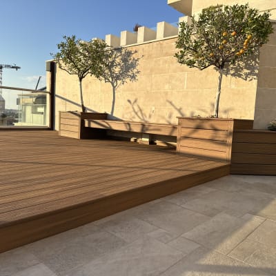 דק עץ עם עציצים ועצים קטנים על מרפסת