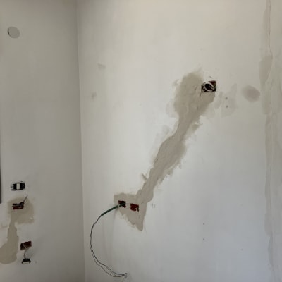 קיר עם חורים ותיקוני טיח, חוטי חשמל חשופים