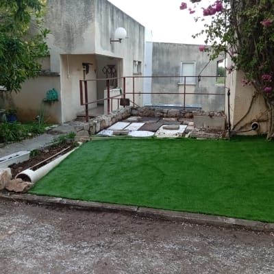 דשא סינתטי, ערוגות, צינור השקיה, עציץ עם פרחים