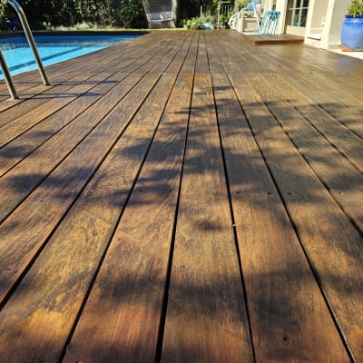 דק עץ ליד בריכה עם סולם מתכת