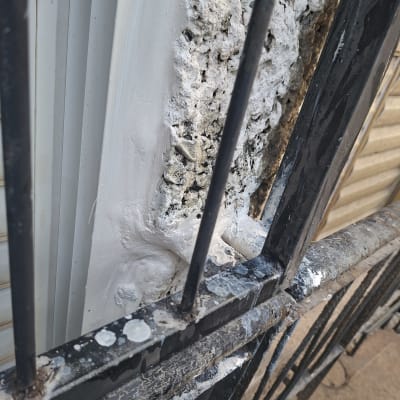 איטום סביב חלון עם חומרי איטום ולכלוך על סורגי מתכת