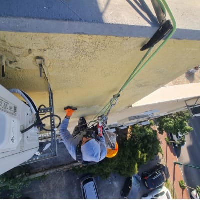 עובד בגובה עם ציוד בטיחות צובע קיר חיצוני