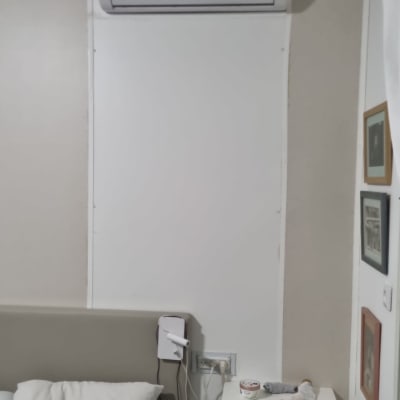 מזגן מותקן על קיר מעל מיטה בחדר שינה