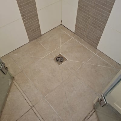 רצפת מקלחת עם אריחים ואיטום סביב הניקוז