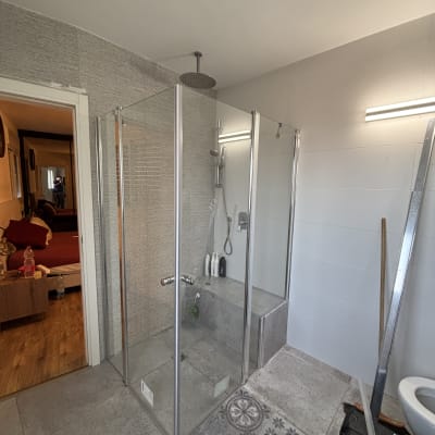 מקלחון זכוכית עם ראש מקלחת עגול ובקבוקי שמפו