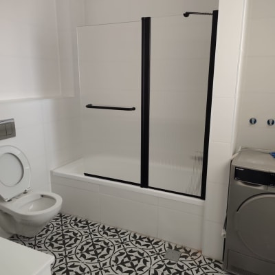 חדר אמבטיה עם מקלחון, שירותים ומכונת כביסה