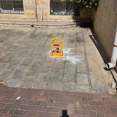 מחסום חניה צהוב על מדרכה מרוצפת