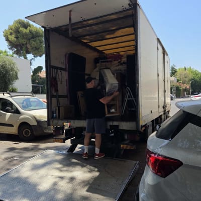 אדם מעמיס משאית עם רהיטים ברחוב ביום שמשי