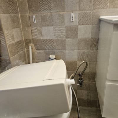 מיכל שירותים מנותק עם צינור גמיש על הרצפה