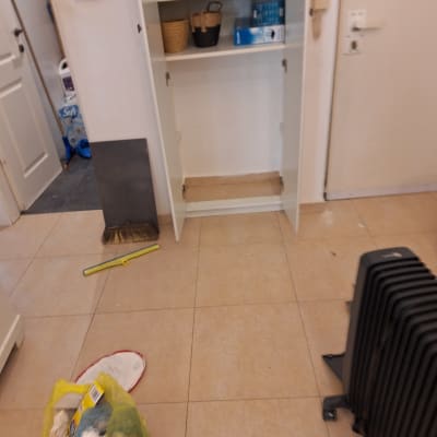 ארון פתוח עם מגהץ, סלסלות ומוצרי ניקוי