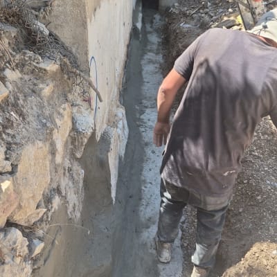 עבודת איטום של קיר חיצוני ויסודות בתוך חפירה לצד בית קרקע