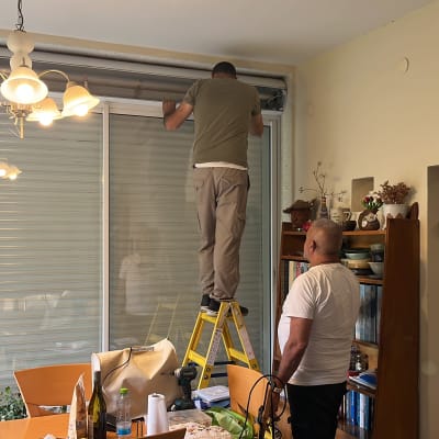 שני אנשים עובדים על תיקון תריס בבית