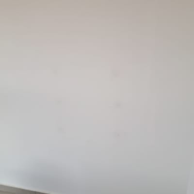 קיר לבן עם סימנים קטנים, רצפת אריחים אפורה