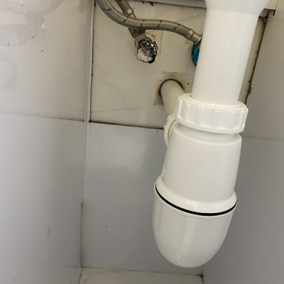 צינור ניקוז לבן מתחת לכיור עם חיבורים