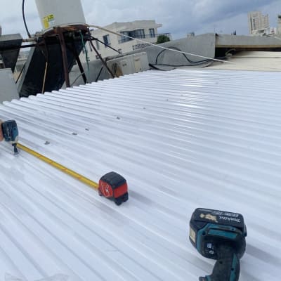 אדם מודד ומבריג על גג עם מקדחה ומטר